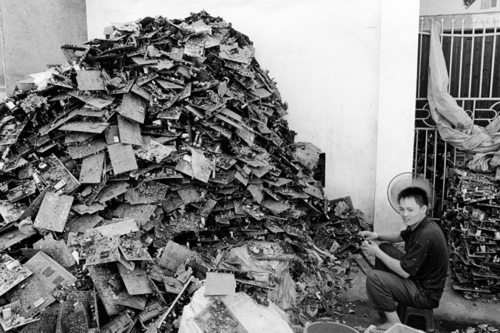 China. Province of Guangdong. The village of Beilin is part of the town of Guiyu. A male worker, seated on a plastic stool, takes down by hand electronic components from printed and integrated circuits of old discarded computers. The various parts will be recycled for its metals, electronic components, chips,...© 2004 Didier Ruef